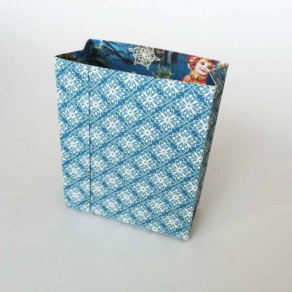 Glue the far left \u00bd\u201d flap of the Sides piece to the front of the gift bag.