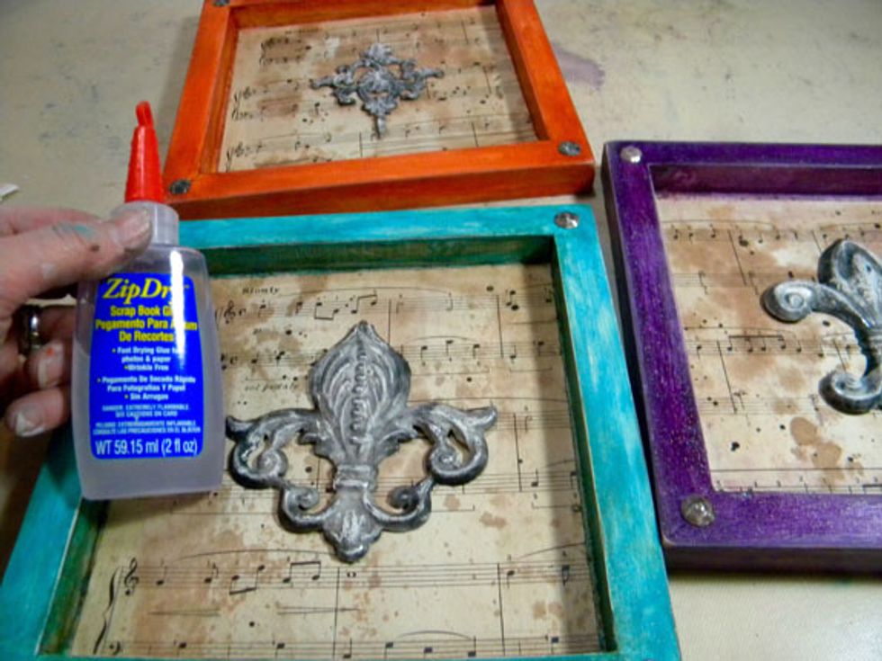 Glue the Flea Market Finds Appliques to the center of the canvases.  Notice the nail heads on the corners?  Let me show you how I gave them the same patina.
