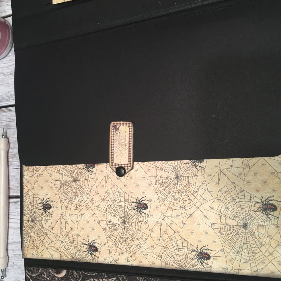 Glue the pattern paper down onto the first page. With the flap closed over the page,the main part of the chipboard piece is over the flap but swings down over the page so you can open up all the pages