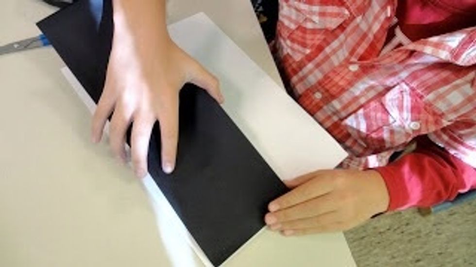 Glue the precut black paper strip to the top of a white paper. The white will become the ground and the black will be the background.