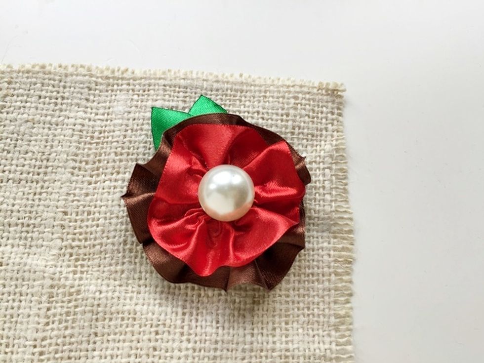 Glue the small ruffled ribbon ring and then glue the bead on the center.