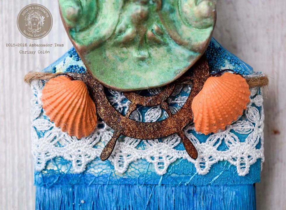 Glue your lacy bits and trims onto the brush. Once they are all settled into their new homes, glue on your newly prettied embellishments include Poseidon\u2019s regal visage.