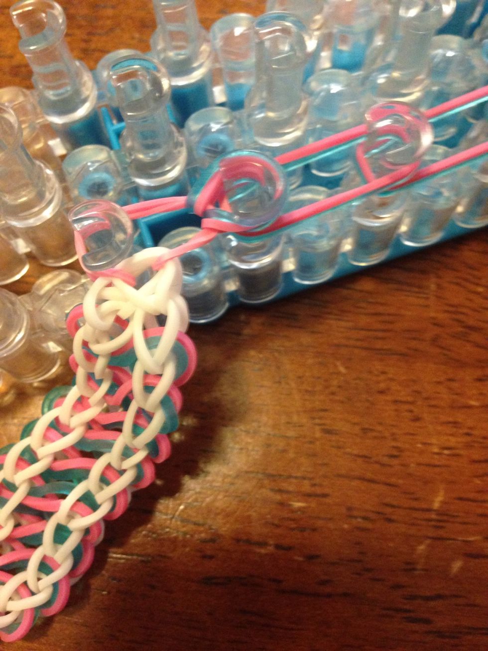 Go inside the two sides of the band you just placed and take the bottom band(s) and pull them over to the next pin.