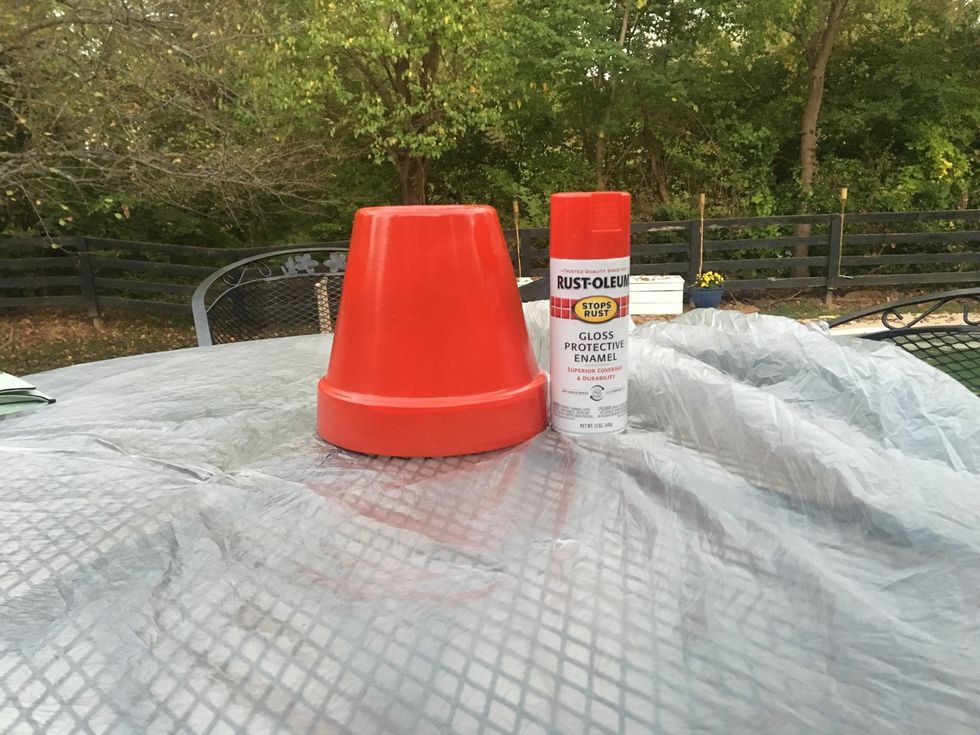 Go outside and put your flower pot on cardboard and spray paint it red and then let it dry.