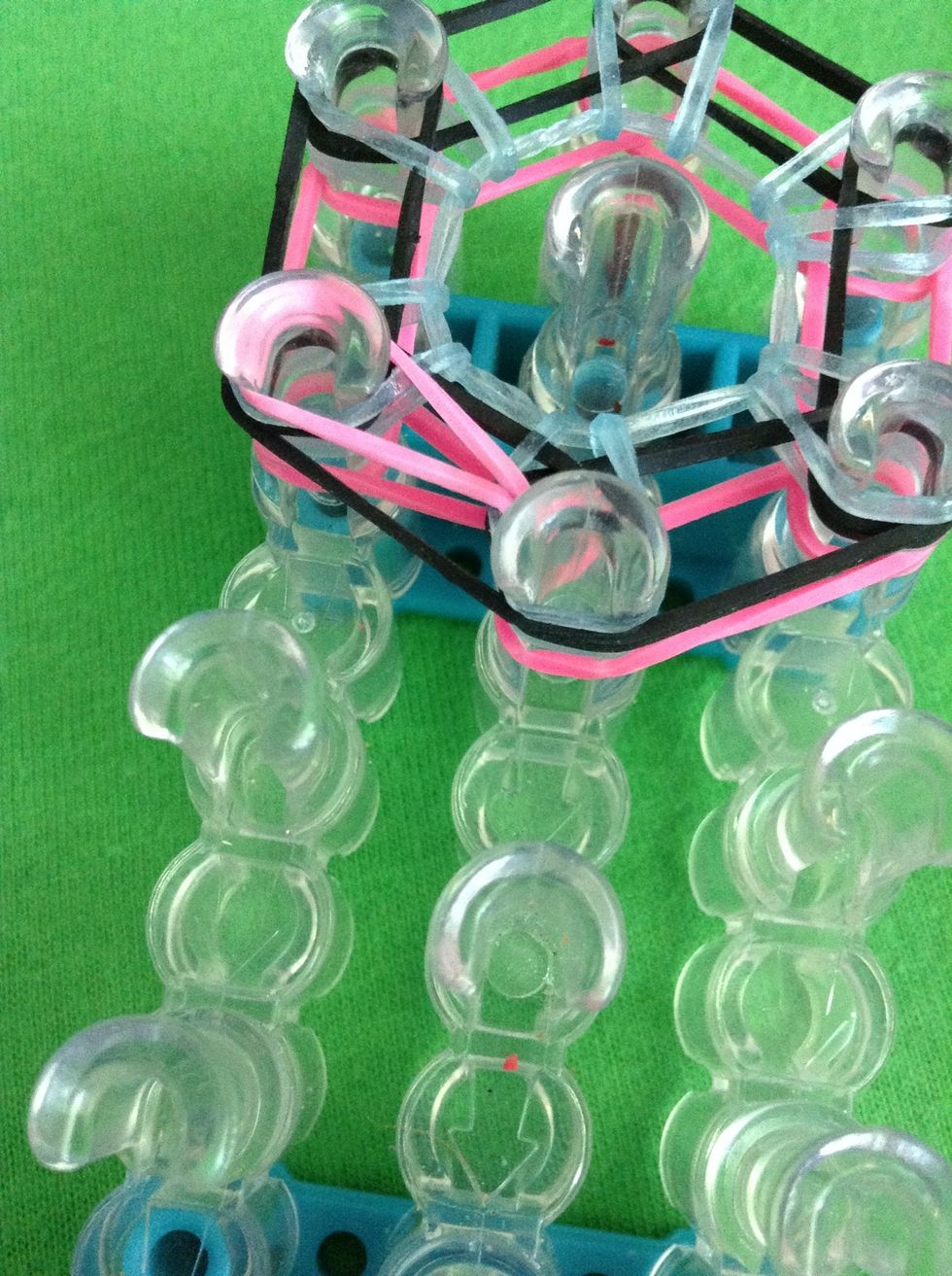 Go under the bands on the peg closest to you or the one across from the one we started with and grab the 2nd to last band. Take this band to the peg the other part of the band is on.