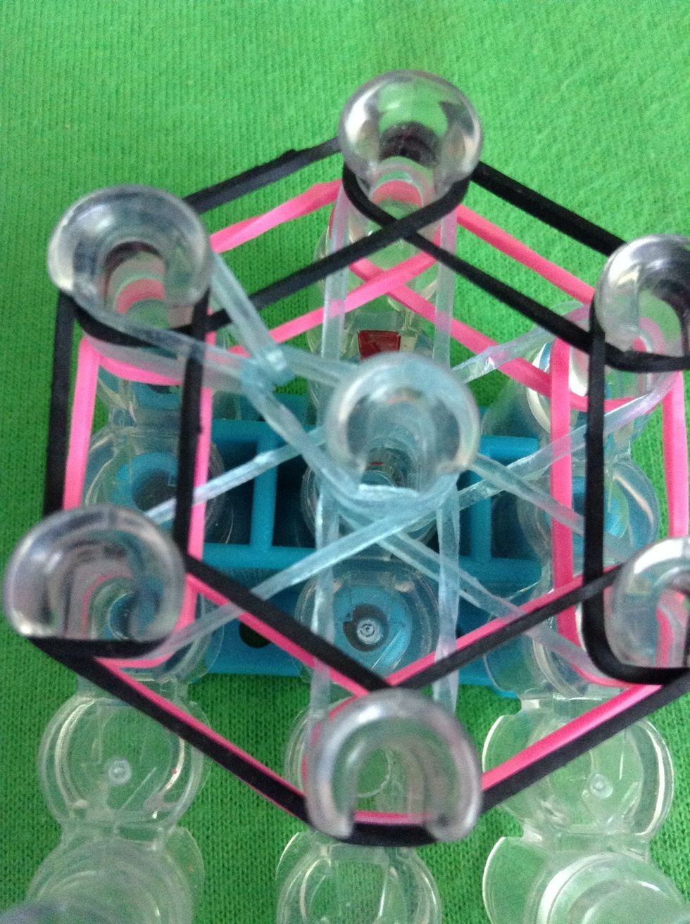 Go under the cap band and grab the first band on top. Put this ban on the peg that the other part of it is on. Continue to do this with all the bands under the cap band.