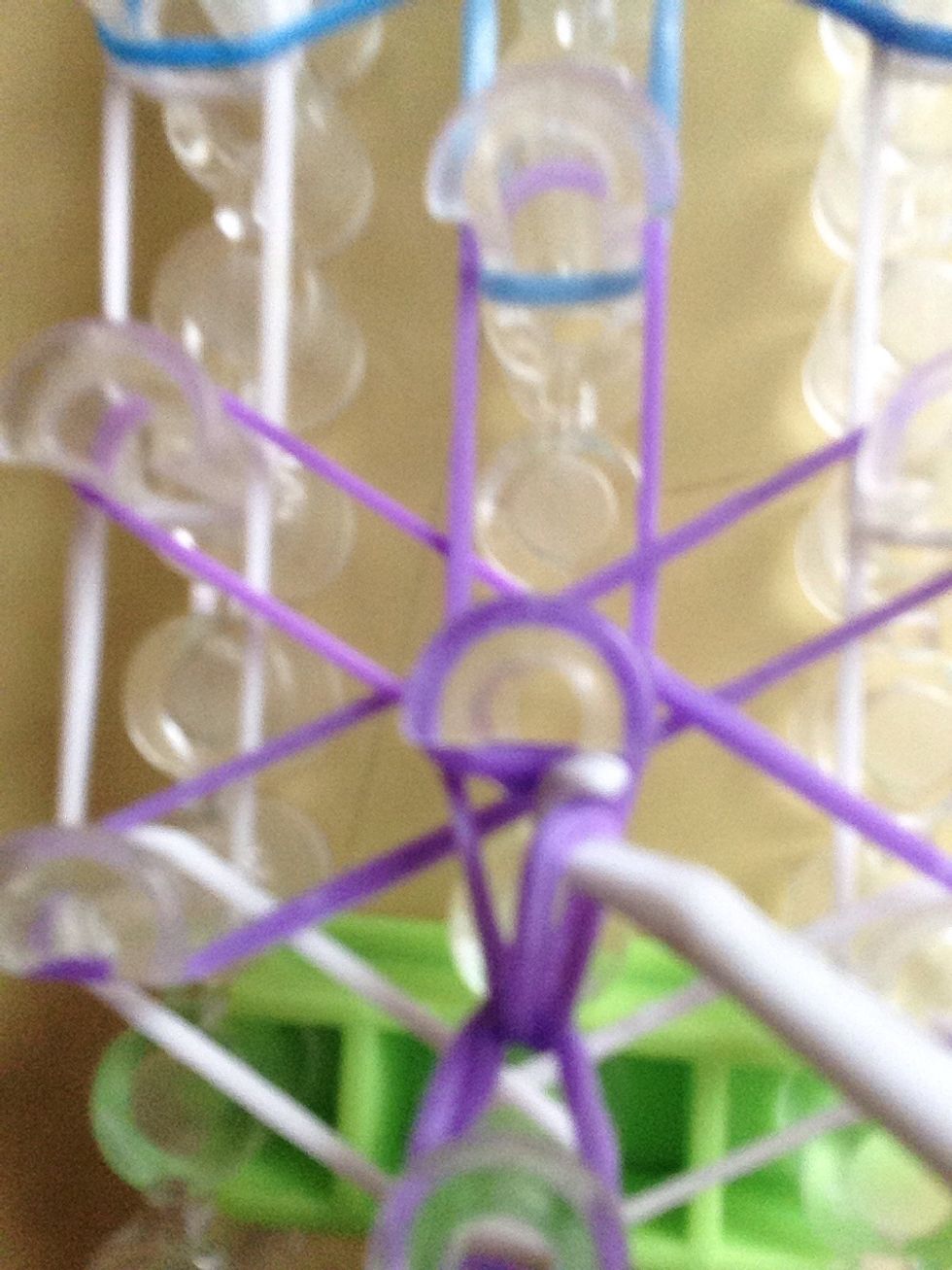 Go under the first peg grab the purple and pull it over to the middle peg.