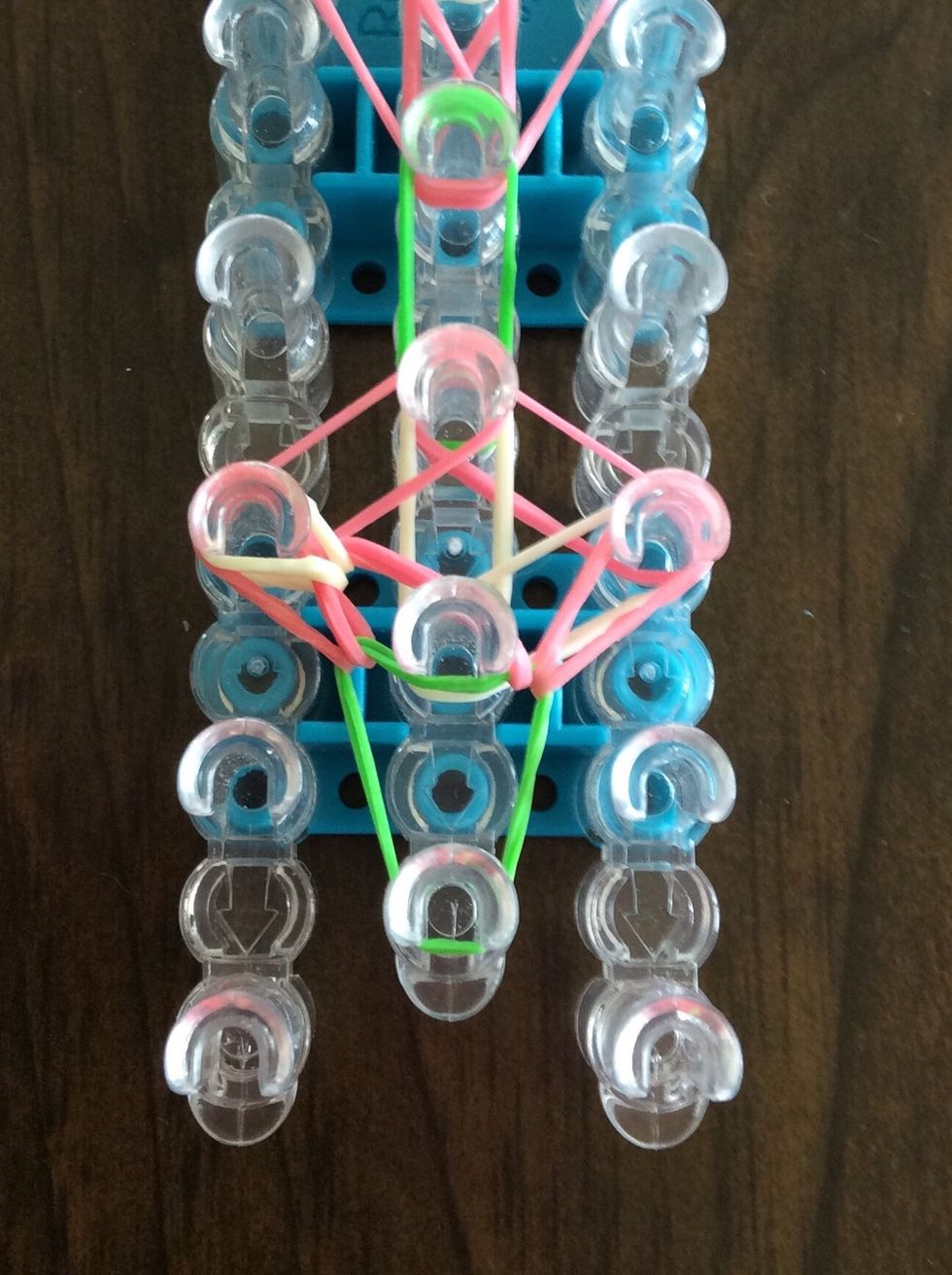 Go under the green band, grab the top white band and bring it to the third left peg.
