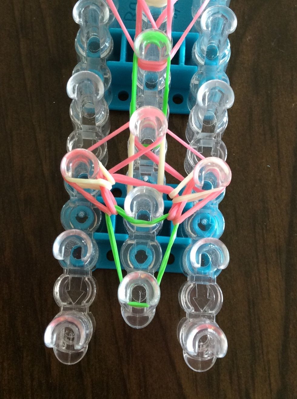Go under the green band, grab the top white band, and bring it to the third right peg.