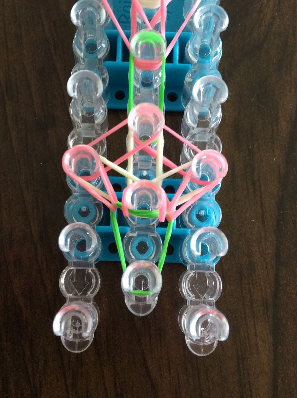 Go under the green band, take the pink band, and bring to the third right peg.