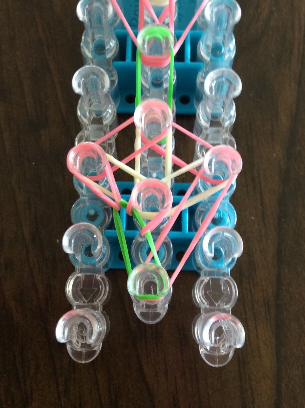 Go under the green band, take the top pink band, and bring it to the second middle peg.