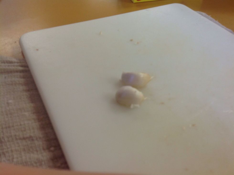Grab 2 garlic cloves and out on to your cutting board.