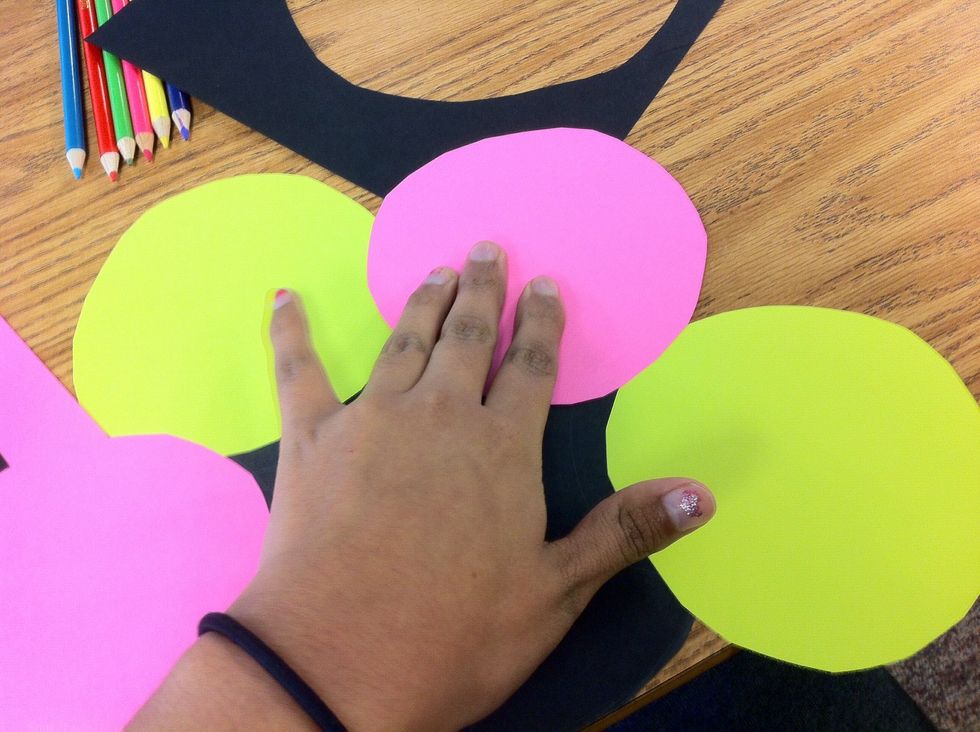 Grab a circle and put it on top of the tape. Repeat this going around the black circle with a different color each time.