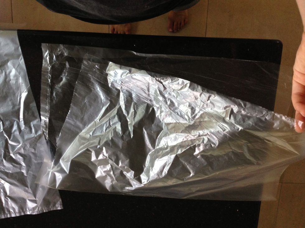 Grab a freezer bag, then cut it length-wise (the longer sides) and again at the section where it's been sealed (the shorter side), so that it opens up. Do this for TWO plastic bags-save one for later