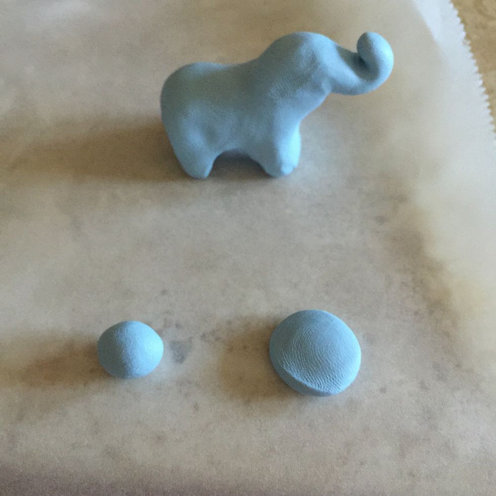 Grab a pinch of clay from the Sculpey package. Roll it into 2 small balls (like on the left) and then push the ball down with your thumb (like on the right).