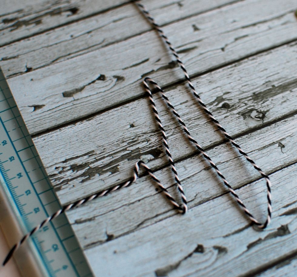 Grab the April Sheet and some Black/White Bakers Twine. About \u00be down the sheet, hot glue the bakers twine down and start making a heart beat design.