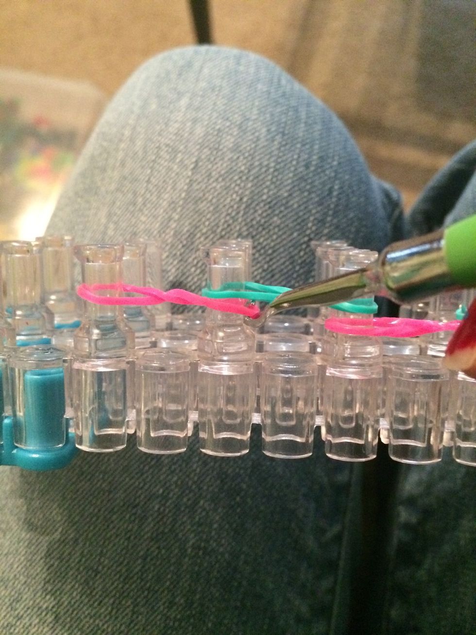 Grab the bottom rubber band on the second peg and loop it over.