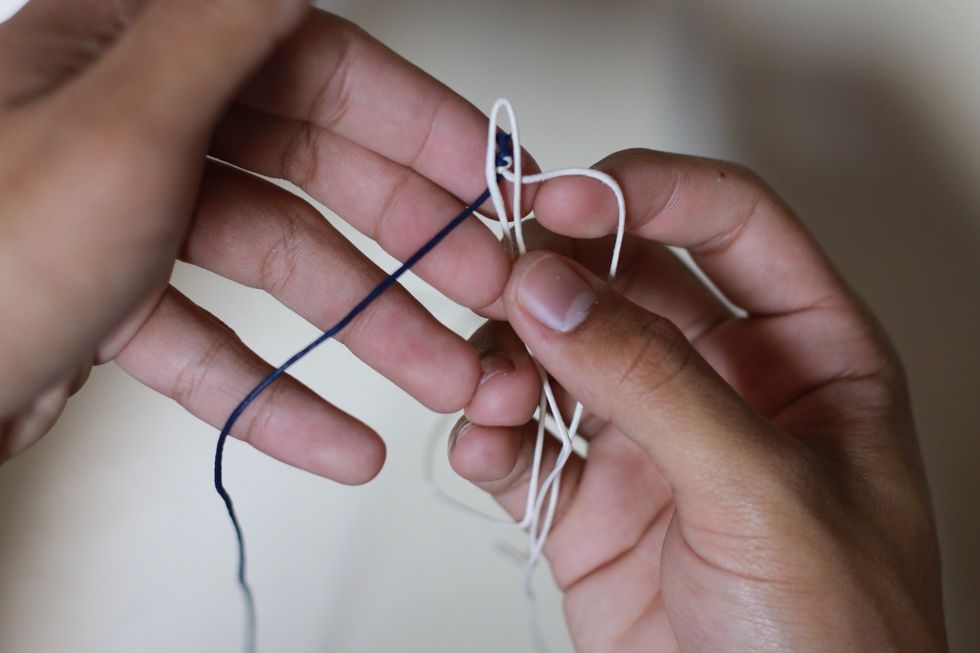 Grab the cord that's tied together and put it behind the folded cord. Like so in the picture.