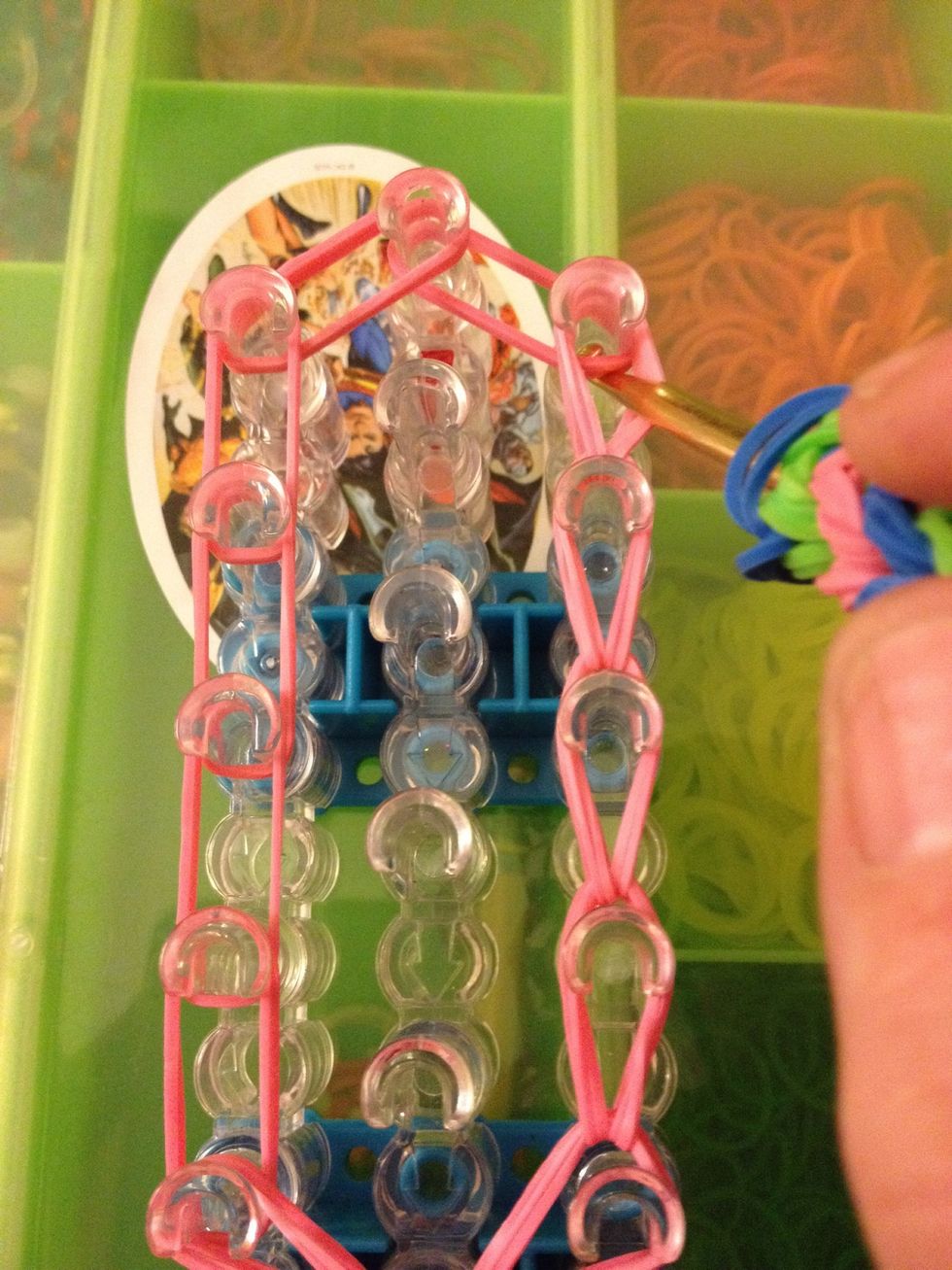 Grab the next set of bands and move them to the center of the loom. Let's do the same thing on the left side.