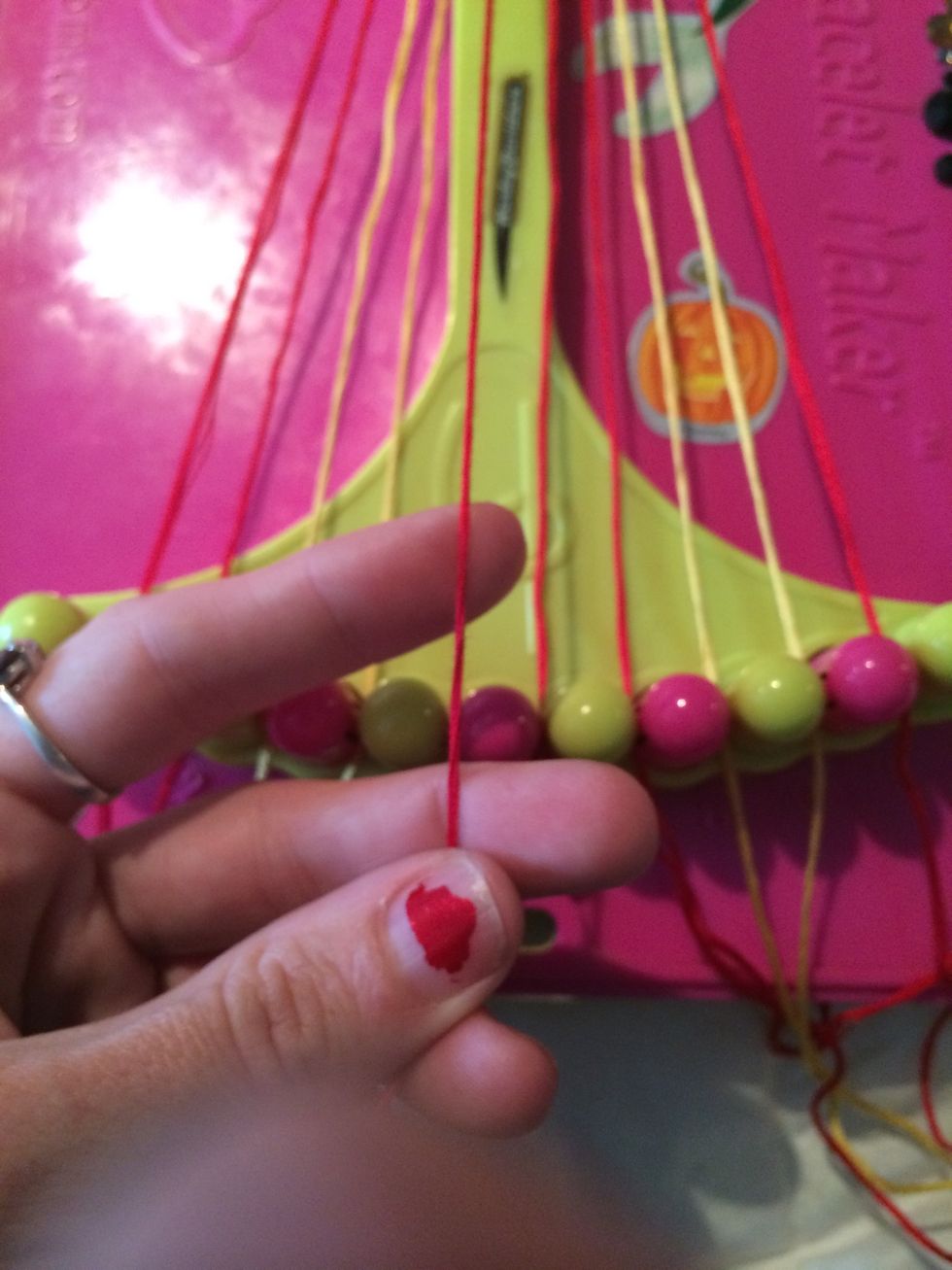 Grab the next string in line. Take the red one and do Backwards knots across all four of the other strings.