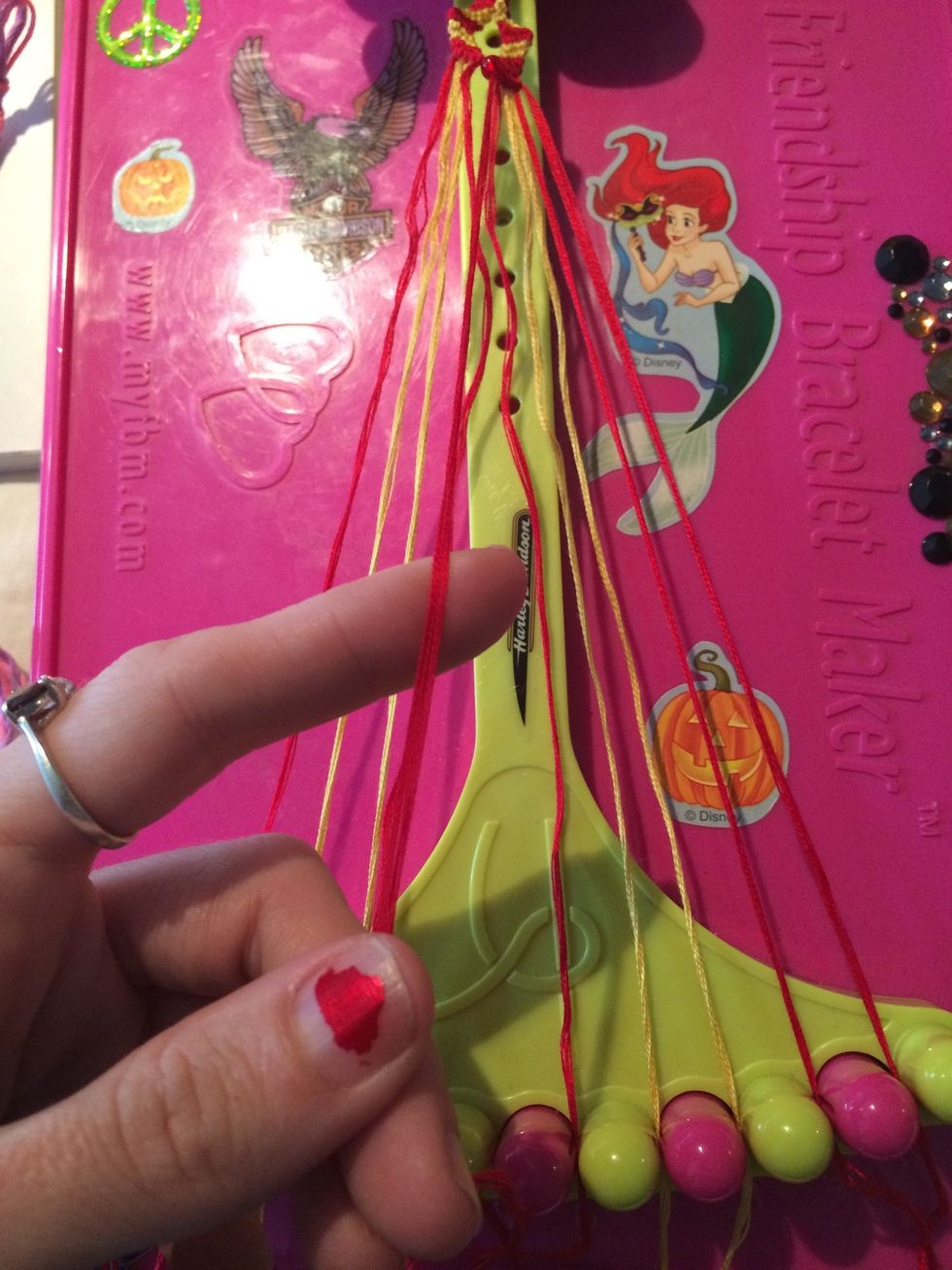 Grab the other red string that is through the bead and make Backwards knots going to the left.