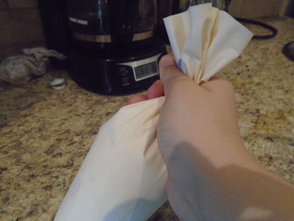 Grab the top where there is no frosting. Pull the bag out of the cup. Twist the top of the bag 3 times and hold. adjust the bag as needed as the frosting is dispensed.