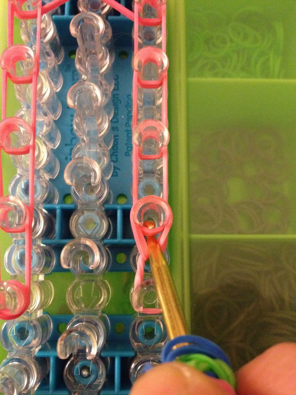 Grab the two rubber bands on the bottom and being them forward.