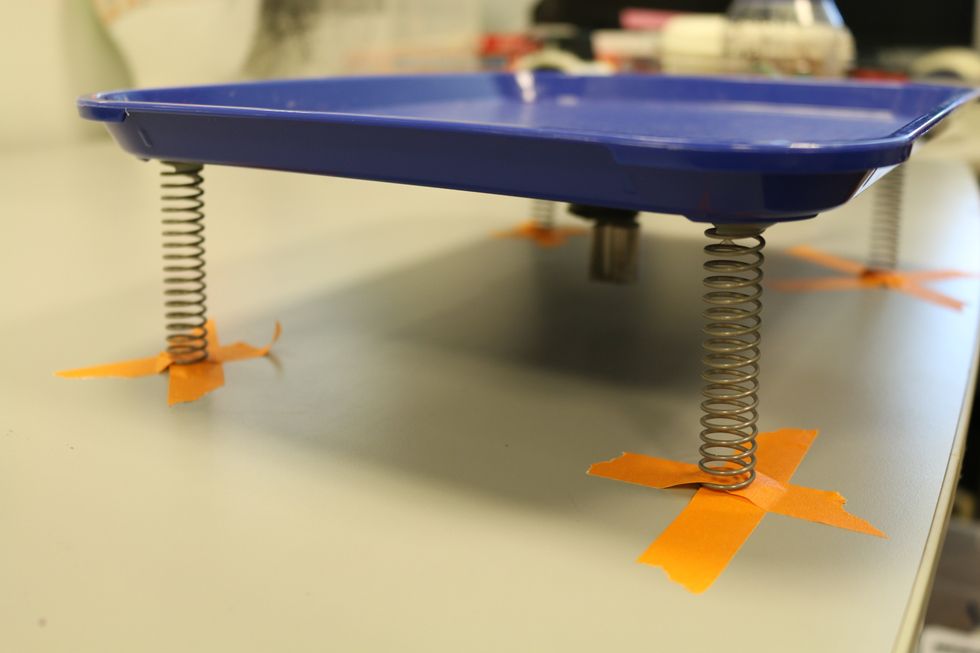Grab two pieces of tapes and cross tape each spring to the table .