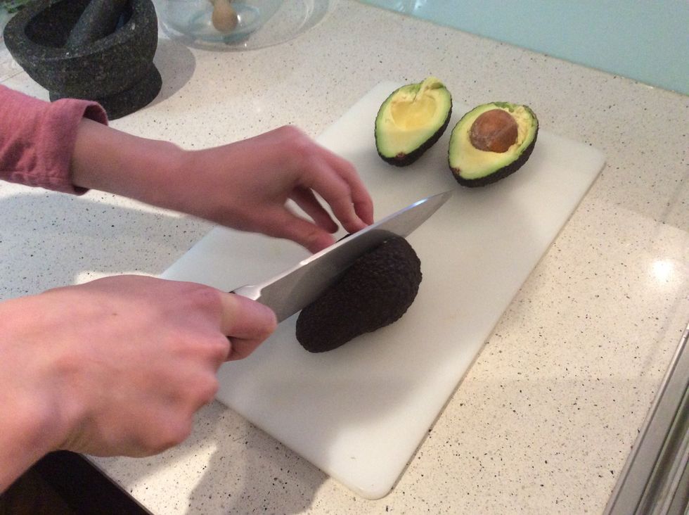 Grab your avocados a cut it through the middle. You will have a pip in the middle of your avocado, so just cut around it.