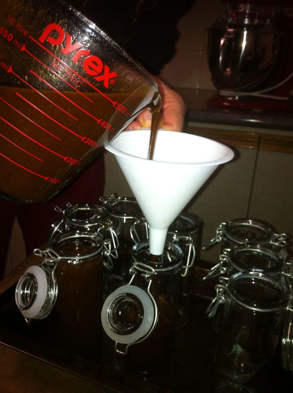 Grab your hot jars out if the oven. Using a funnel (or without if you have a steady hand) pour the sauce into your heated jars and seal them as you go. Place them somewhere to cool