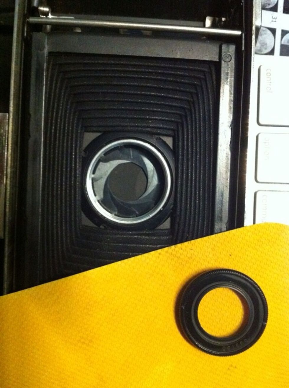 Grab your rubber mat, place it gently on the ring and encourage it to turn left. Support the camera or you will damage the closed bellows. Try not to touch them. Put your lens to one side