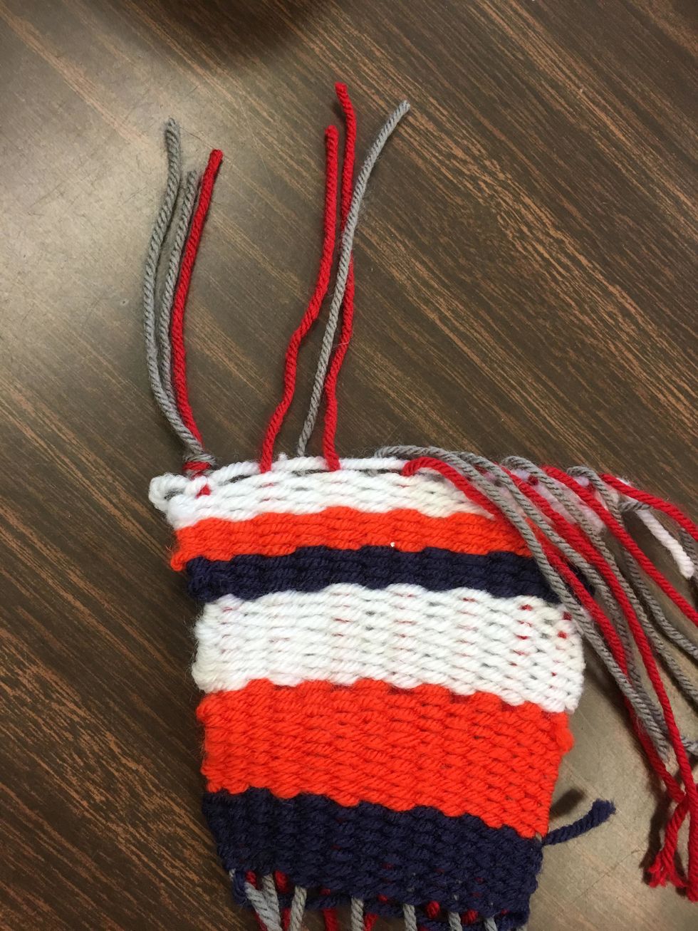Grabbing 3 yarns at a time, tie knots as close to the project as you can to keep your weave tight. Do this across both the top and the bottom.