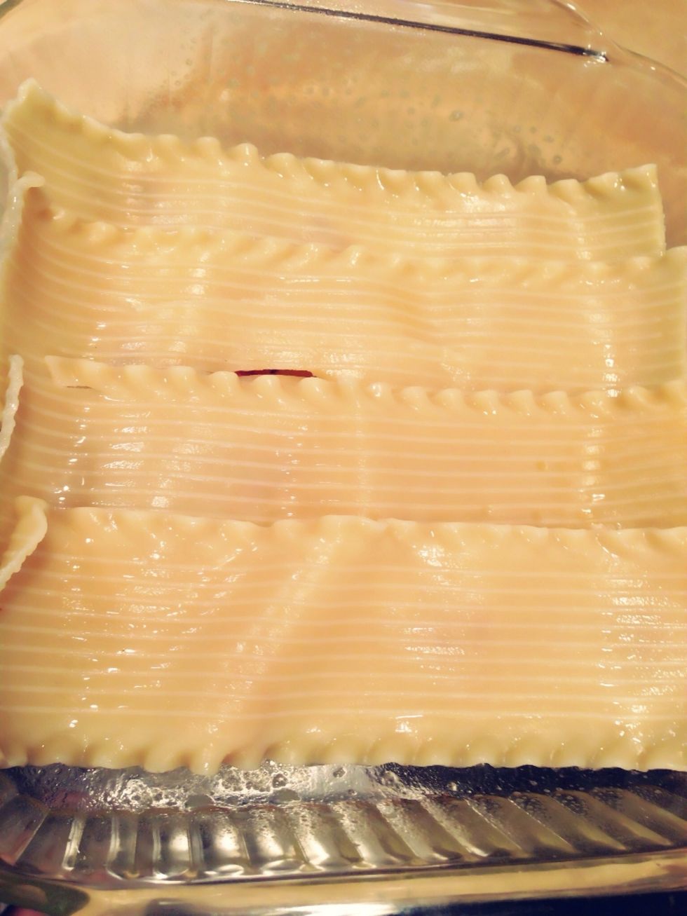 Grease a 9x14 pan well. Start by layering noodles on the bottom of the pan, slightly overlapping. The noodles may not be long enough for the pan, so a noodle may need to be cut to fit.