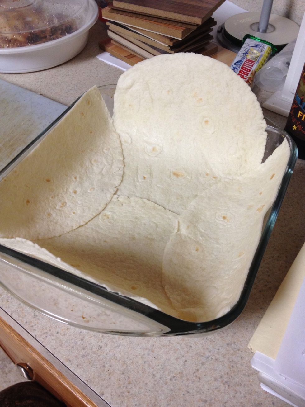 Grease a dish and place the tortillas inside covering the bottom, trim the sides to the top of the dish.