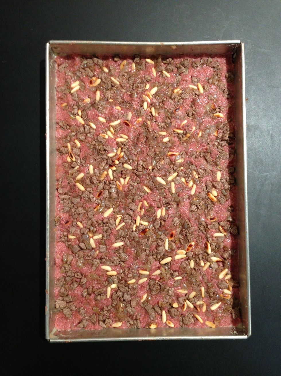 Grease the mould. Spread the first kibbeh paste layer. Put the stuffing and press it well until it sinks in the paste... Like above. Traditionally round moulds are used. Optional.