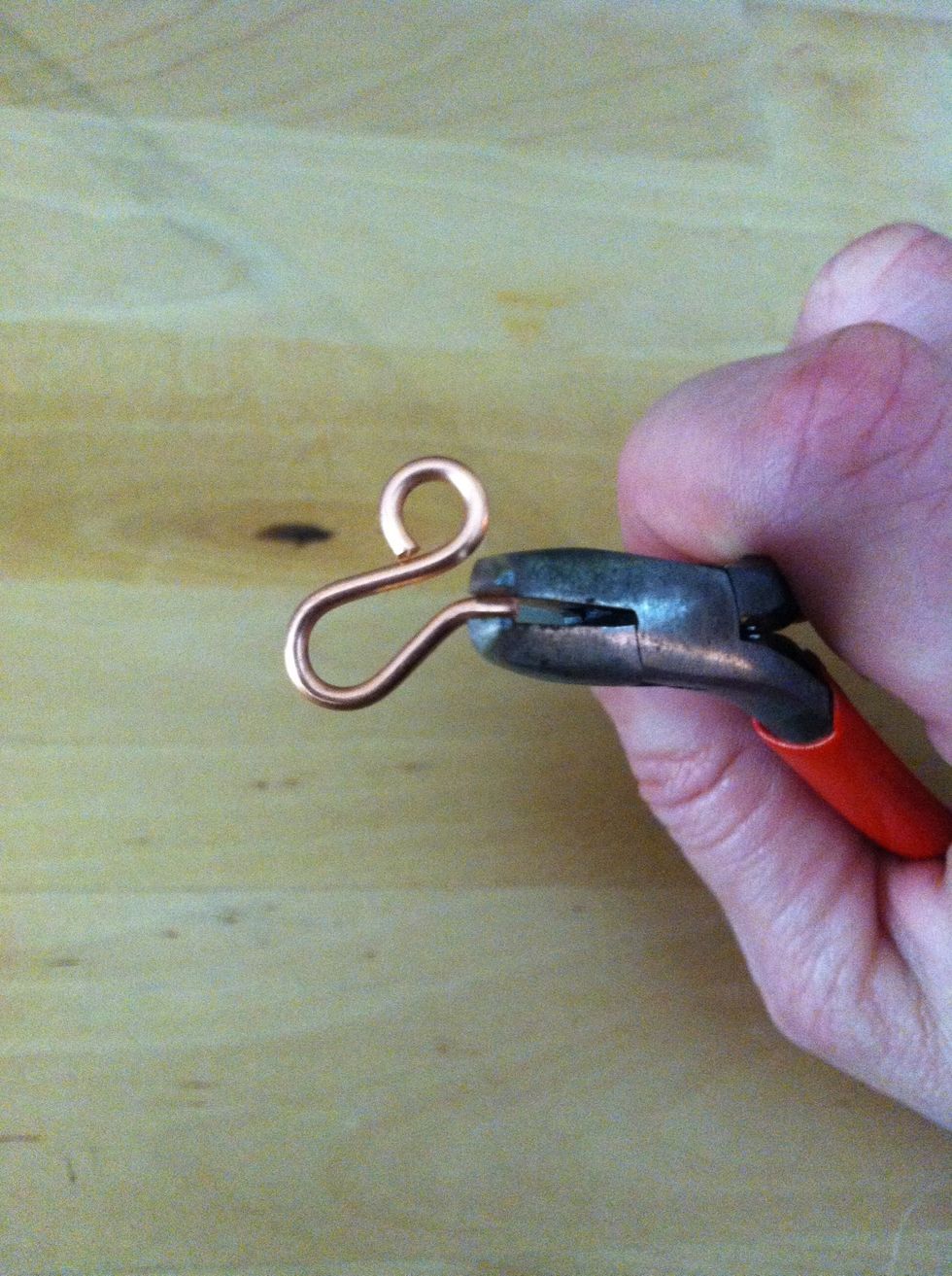 Grip the tip of the hook with the bent nose pliers. Hold the hook steady with your other hand and use the pliers to bend the tip up at a slight 45 degree angle.