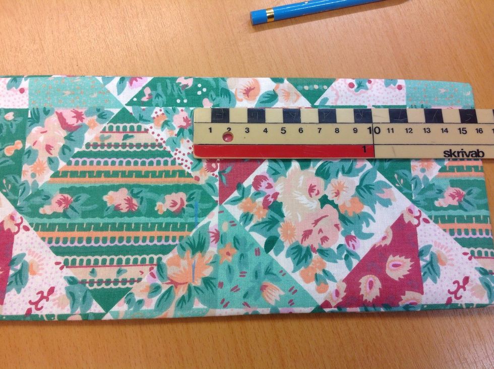 H\u00e4mta en linjal och en textilpenna. M\u00e4t 16 cm fr\u00e5n den vikta kanten. G\u00f6r ett litet streck med textilpennan.