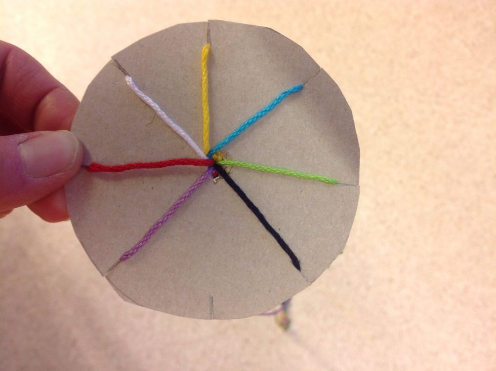 H\u00e5ll skivan framf\u00f6r dig med det tomma jacket mot magen. L\u00e5t tr\u00e5darna h\u00e4nga fritt mot golvet. Tag den tredje tr\u00e5den \u00e5t h\u00f6ger (turkos) i handen.