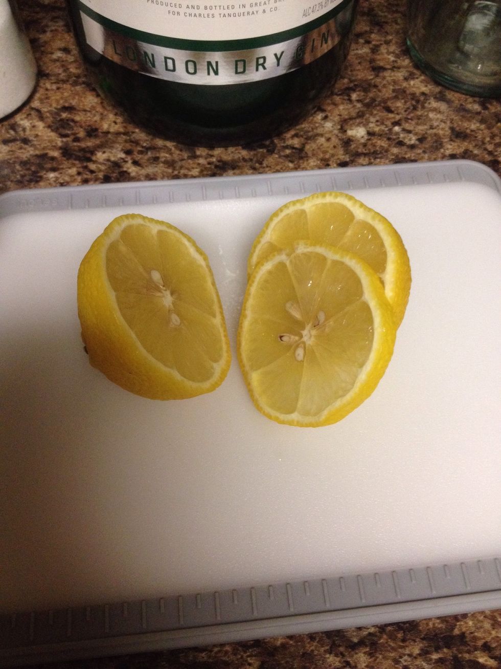 Halve the lemon. Slice a lemon wheel to garnish the cocktail. (A twist would also work.)