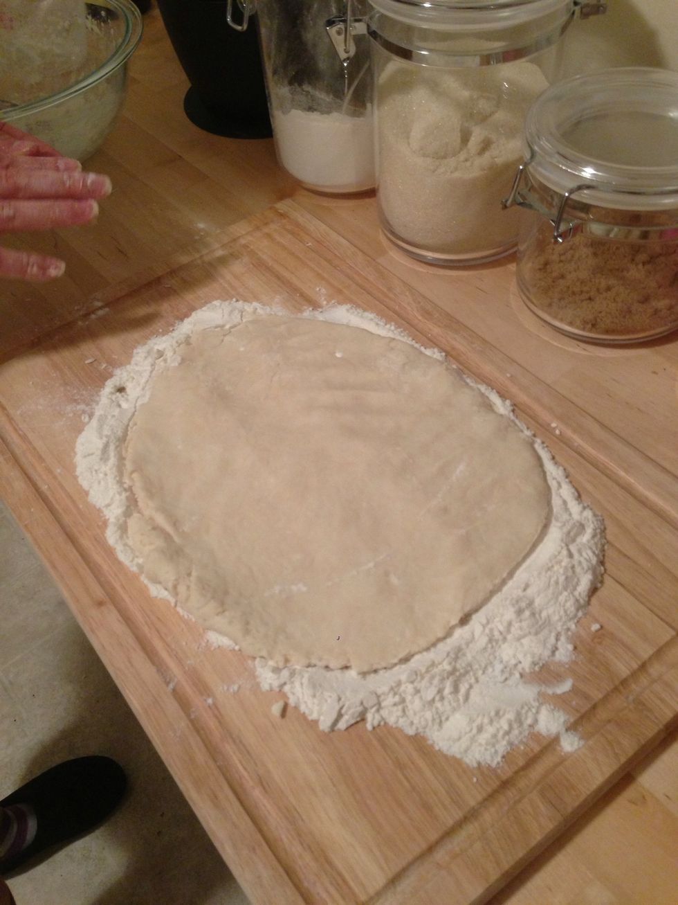 Hand stretch the dough over the flour.