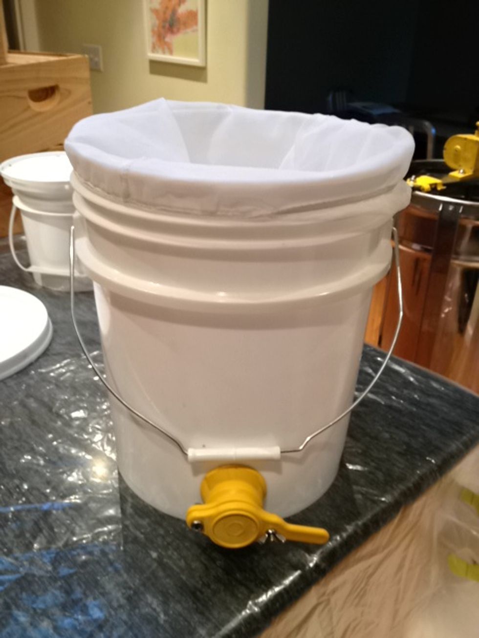 Have a 5 gallon bucket ready, with a nylon strainer placed inside. You can purchase a bucket with a spigot from a beekeeping supply company. It makes bottling much easier then with a regular bucket.