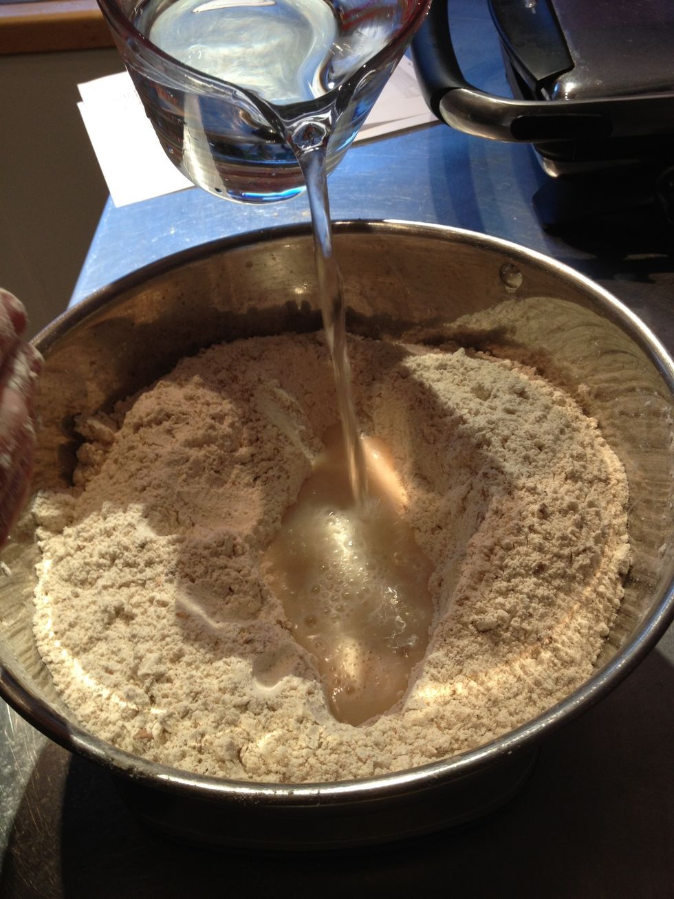 Have a jug with 625ml tepid water ready. Make a well into the flour and start adding water bit by bit, mixing it in with your hand.