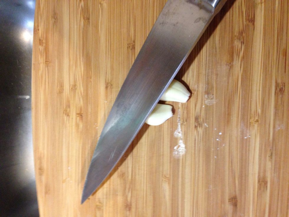 Have you ever crushed garlic? It's fun. Place the blade of your knife over the garlic.