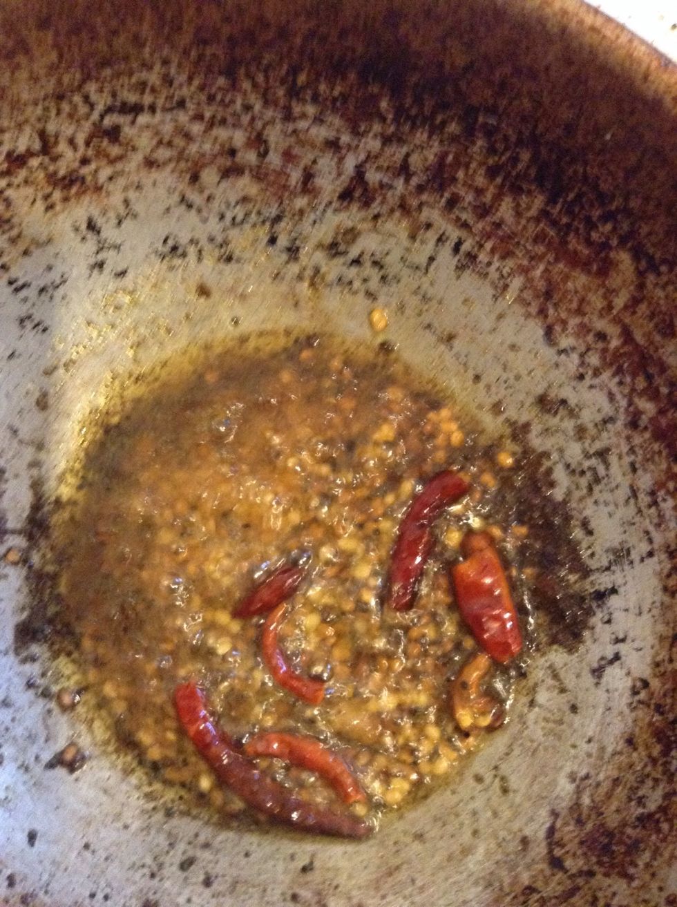 Heat 3 tablespoons of Sunflower oil, then add mustard seeds. When the mustard seeds start to spurt, add asafoetida, urad dal, fenugreek and dried red chillies. Fry until the urad dal turns red.