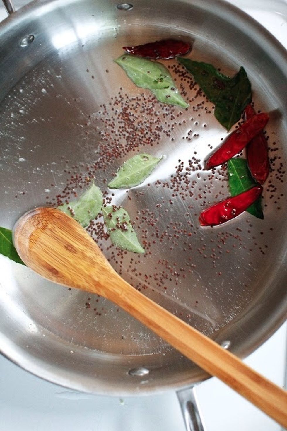 Heat 3 Tbs of oil in a large wok, skillet or kadhai. When the oil is hot, Cook until the mustard seeds start to pop, add in the curry or bay leaves,mustard seeds and dried red peppers.