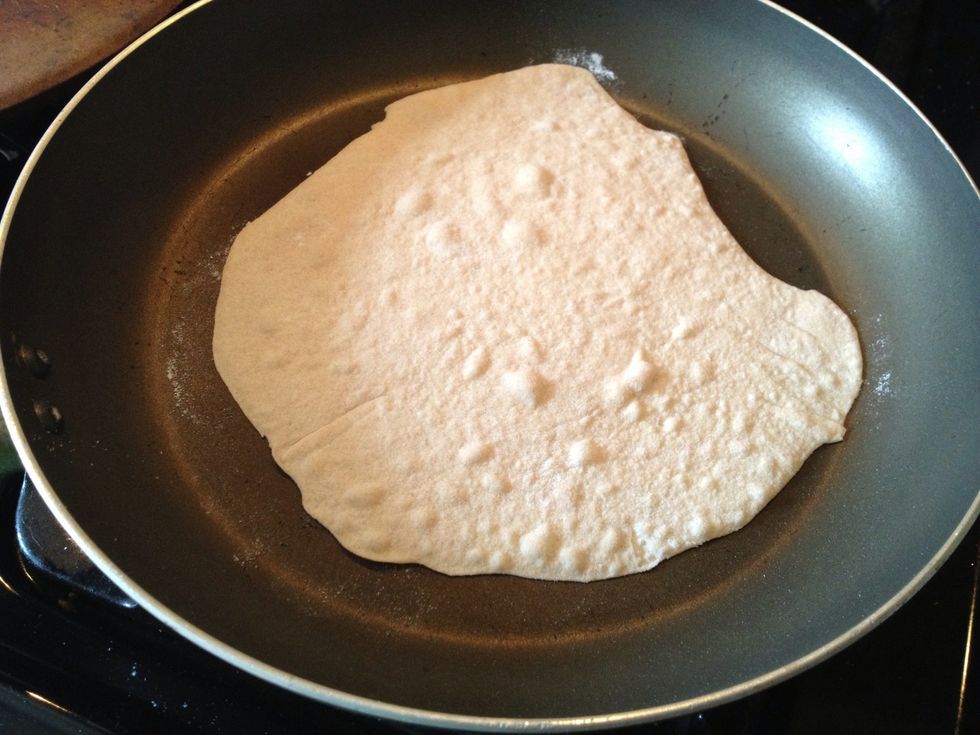 Heat a non-stick skillet big enough to hold the tortilla to medium-high. Place the dough round in the pan. It will begin to form tiny air bubbles after about 1 minute.