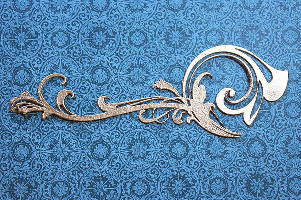 Heat emboss a chipboard flourish using gold embossing powder.