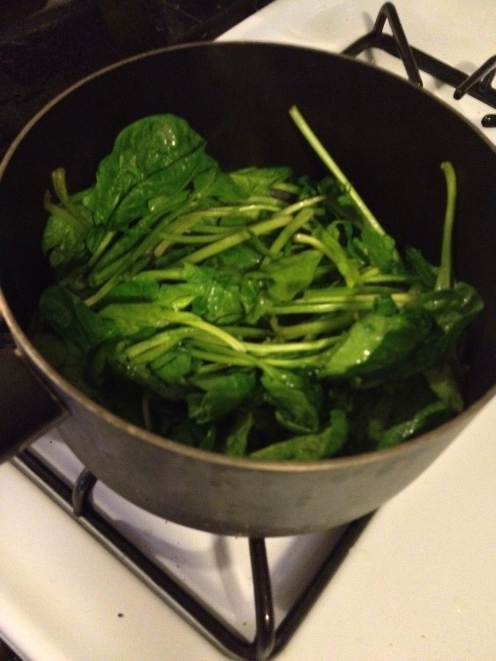 Heat oil in a Dutch oven over medium heat. Add garlic and cook until beginning to brown, 1 to 2 minutes. Add spinach and toss to coat. Cover and cook until wilted, 3 to 5 minutes.