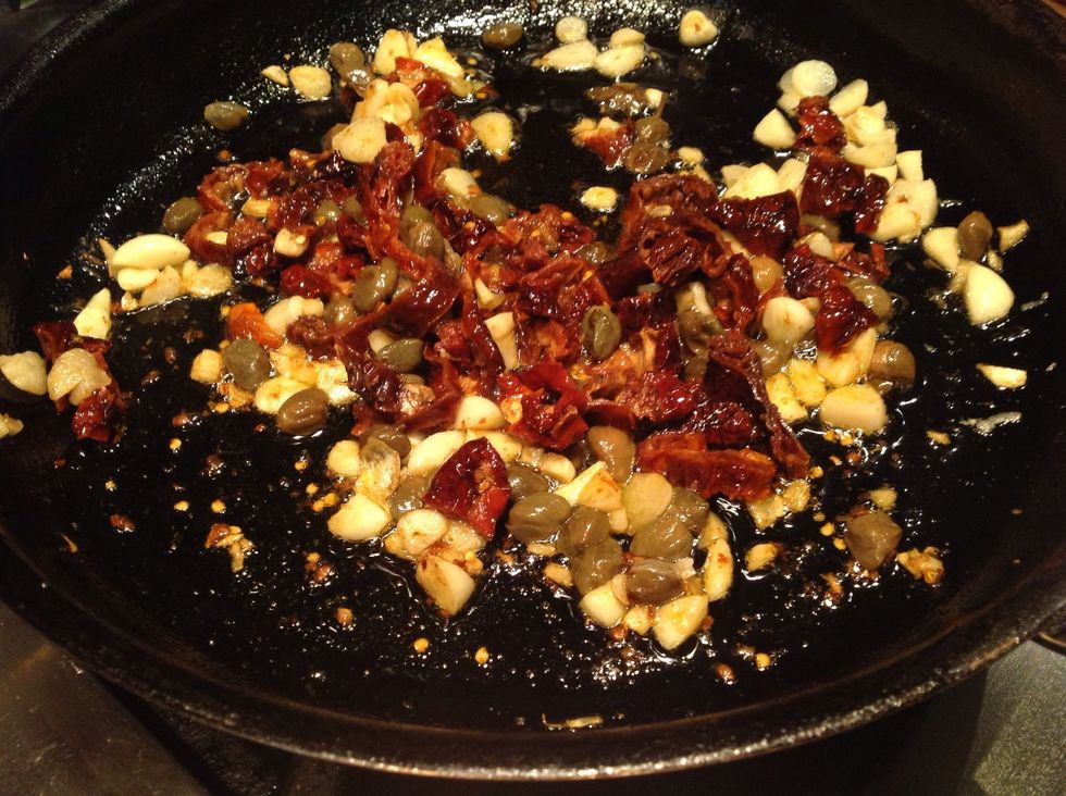 Heat oil to medium high. Add anchovy and break up with tongs. Add garlic and fry until it begins to brown. Then add capers and tomatoes. Add 1/3 cup of pasta cooking water to the pan to deglaze.