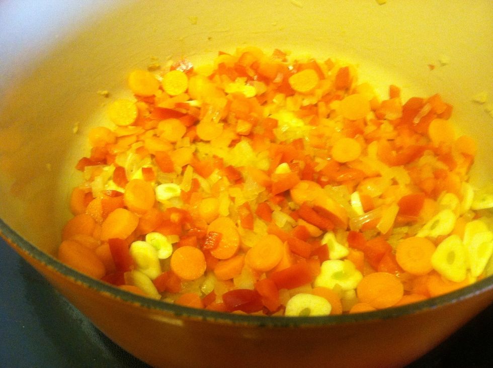 Heat olive oil over medium.  Add onions and saut\u00e9 for 5 minutes.  Add carrots, peppers and garlic, cook for another five minutes.